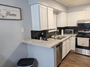 a kitchen with white cabinets and a sink and a stove at Entire One Bedroom Condo with AC, Wifi, & Pool in San Antonio