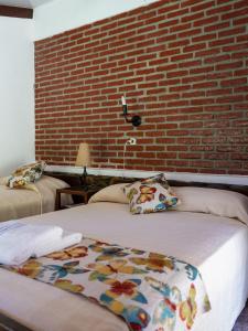 two beds in a room with a brick wall at Hotel de selva EL PUENTE in Villa Tunari