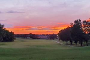 a sunset on a golf course with trees in the foreground at On Golf Course Peaceful Central Upscale in Columbus