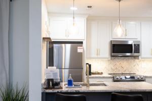 a kitchen with white cabinets and a stainless steel refrigerator at Golf Course Views, Sunsets & Chill Vibes in Columbus
