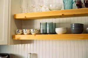 a wooden shelf with bowls and glasses on it at The Tea CottageStylishRain ShowerLocation in Starkville