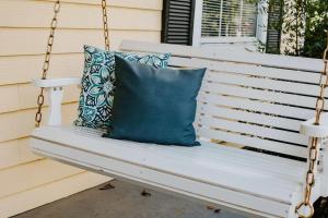 a porch swing with two pillows on it at The Tea CottageStylishRain ShowerLocation in Starkville