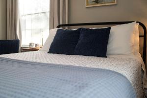 a bed with blue and white sheets and a window at The Tea CottageStylishRain ShowerLocation in Starkville +50 photos