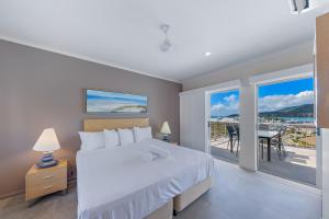 a bedroom with a bed and a balcony with a table at at Boathaven Bay Holiday Apartments in Airlie Beach +32 photos