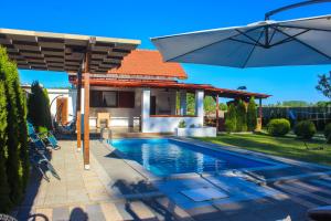 a swimming pool with an umbrella next to a house at Vikendica Drinski LAD in Loznica