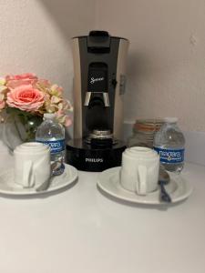 a coffee maker and two cups and flowers on a counter at Tree House in Saint Martin