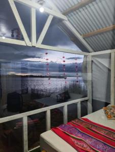 a bedroom with a window with a view of the ocean at Uros titikaka Golden Lodge in Puno +5 photos