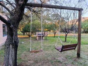 a swing hanging from a tree in a park at Cabaña La Escondida in Villa de la Quebrada