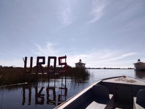 a boat on a lake with a sign in the water at Uros titikaka Golden Lodge in Puno