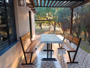 a table and two benches on a patio at Cabaña La Escondida in Villa de la Quebrada