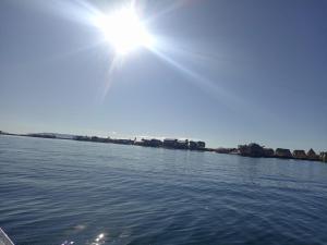 a sun is shining over a body of water at Uros titikaka Golden Lodge in Puno