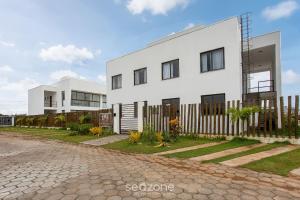 a white house with a fence in front of it at Modern and sophisticated apartments near the beach in Maraú – VLL in Marau