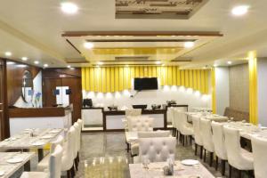 a dining room with white tables and white chairs at Hotel Taj Venture Agra in Agra
