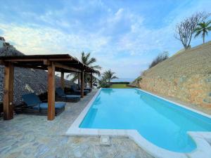 a swimming pool with a thatch roof and a resort at Villas & Resort Luz de Luna in Santa Cruz Huatulco