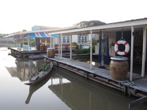 Ein Boot liegt neben einem Haus auf dem Wasser vor Anker. in der Unterkunft U Pae PaeStay Uthaithani in Uthai Thani
