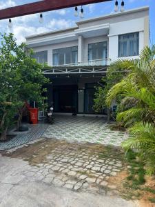 a large white building with a stone courtyard at KEN Homestay in Cu Lao Thu