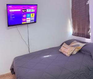 a bedroom with a bed with a tv on the wall at Nice and Cozy House in the Greater Ponce Area in Ponce