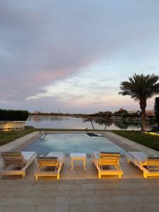 a swimming pool with four lounge chairs and a table at Golf El Gouna 2 in Hurghada