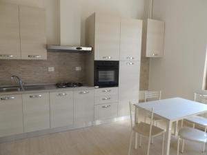 eine Küche mit weißen Schränken sowie einem Tisch und Stühlen in der Unterkunft Felicity5terre in La Spezia