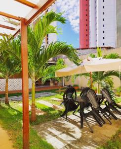 a patio with chairs and a table and palm trees at Hostel Borogodó in Fortaleza