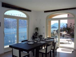 a dining room with a table and two large windows at Villa Panoramica in Menaggio