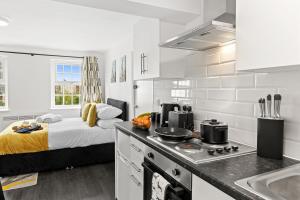 a white kitchen with a bed in the background at Cheshire Gold- studio apartment, Warrington in Warrington +20 photos