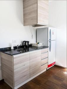 a kitchen with wooden cabinets and a white refrigerator at Apart Casa de Piedra in San Luis