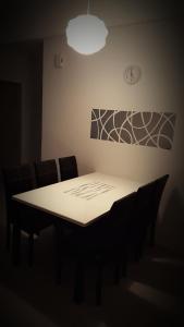 einen Esstisch mit Stühlen und eine Uhr an der Wand in der Unterkunft Dephane Apartment in Cameron Highlands