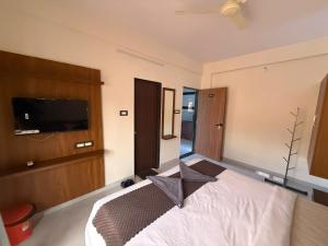 a bedroom with a bed and a flat screen tv at Shreya Bungalow Mahabaleshwar in Mahabaleshwar