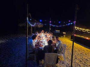 a group of people sitting at a table on the beach at night at fehivilla resistance in Dhangethi +240 photos