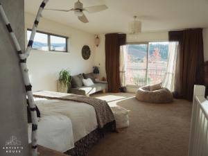 a bedroom with a bed and a couch and a window at The Artist's House Wanaka in Luggate