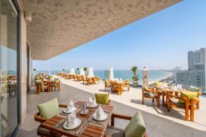 a restaurant with tables and chairs on a balcony at Awaken Da Nang Hotel in Danang +95 photos