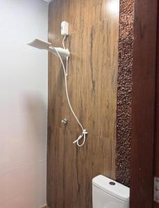 a bathroom with a white toilet and a wooden wall at Chalé Mansões do Rio in Casa Nova