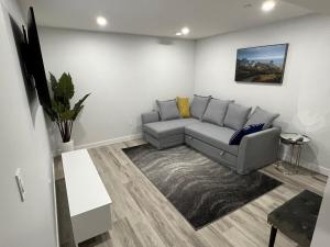 a living room with a gray couch in a room at Charming 1Bd Basement Suite with Private Entrance in Calgary