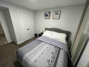 a bedroom with a bed with a gray bedspread at Charming 1Bd Basement Suite with Private Entrance in Calgary