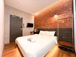 a bedroom with a white bed and a brick wall at Havona Boutique Hotel - Mount Austin - Self Check-in in Johor Bahru