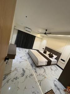 a bedroom with a large bed with a marble floor at Hotel D Lite Inn in Junagadh
