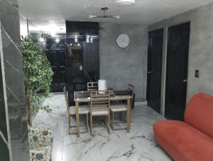 a dining room with a table and chairs and a clock at Casa Rota in Mérida