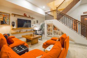 a living room with orange furniture and a staircase at The Magic Villa in Lebih