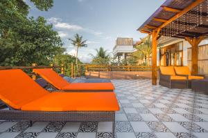 an outdoor patio with orange chairs and a building at The Magic Villa in Lebih