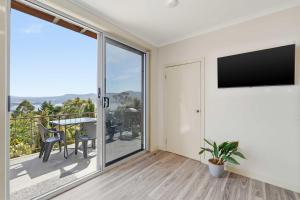 a living room with a flat screen tv and a balcony at MONA Vista, Tasmania in Rosetta