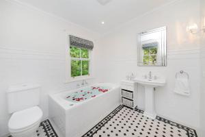 a white bathroom with a tub and a sink at Poets Cottage c1912 Scenic Hikes, Fire, Spa Bath in Wentworth Falls