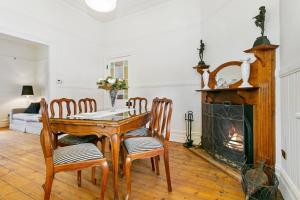 a dining room with a table and chairs and a fireplace at Gowan Brae Cottage - NEW! in Katoomba