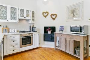 a kitchen with white cabinets and a microwave at Gowan Brae Cottage - NEW! in Katoomba