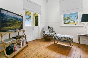 a living room with a flat screen tv and chairs at Gowan Brae Cottage - NEW! in Katoomba