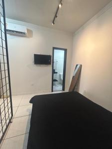 a room with a bed and a tv on a wall at Studio Industrial Moderno in Serra