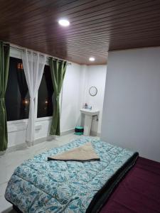 a bedroom with a bed and a window with curtains at Aadharjun Homestay in Chidām