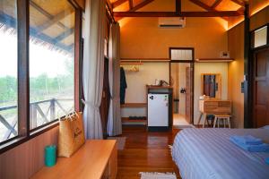 a bedroom with a bed and a kitchen with a refrigerator at Baannok at Motakhian in Pak Chong