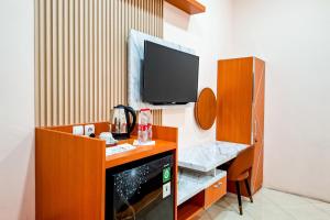 a room with a tv and a desk with a microwave at Abbas Syariah Hotel near Menara Kudus Mitra RedDoorz in Kudus