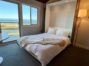 a bedroom with a bed with a view of the ocean at Oceanfront Studio with Loft - amazing views! in Qualicum Beach